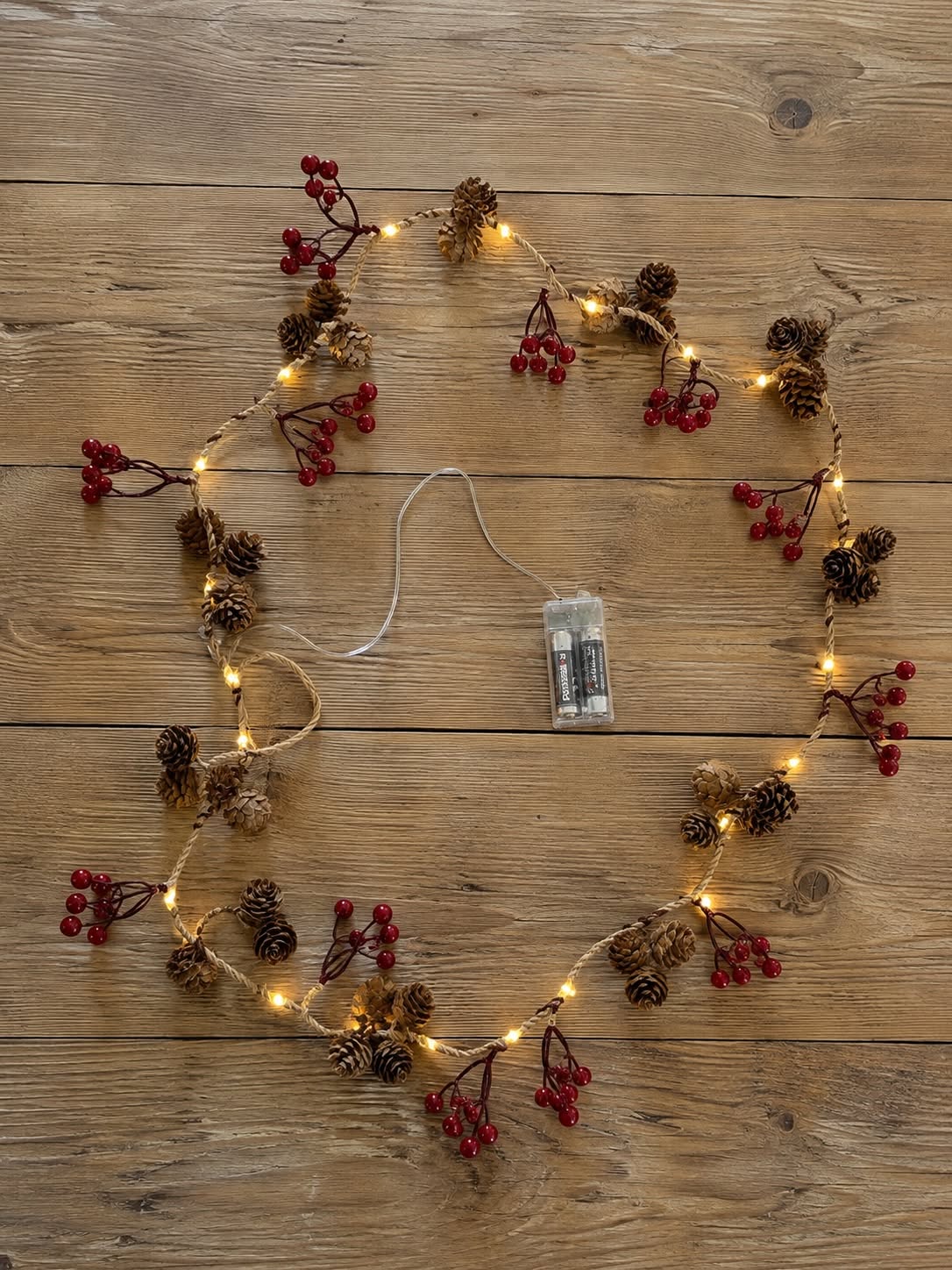 Lichterkette mit roten Beeren und Zapfen